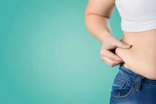Image of woman pinching her love handles to show weight gain Leamington Spa