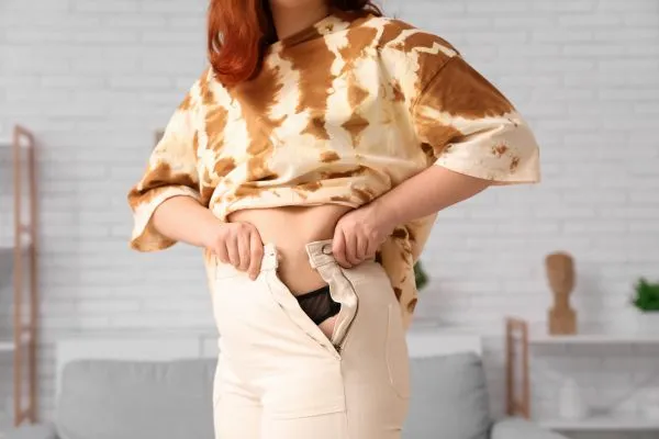 Image of woman trying to do her trousers up after pregnancy weight gain Leamington Spa